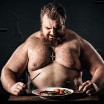 Shirtless muscular man eating a nutritious meal, symbolizing strength and health.